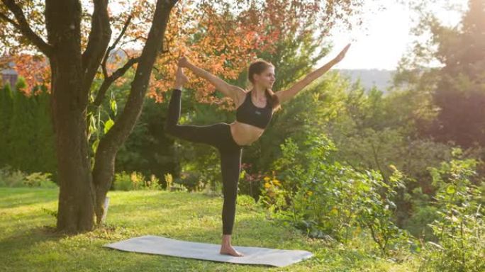 运动活跃的女人在郁郁葱葱的绿色后院练习瑜伽