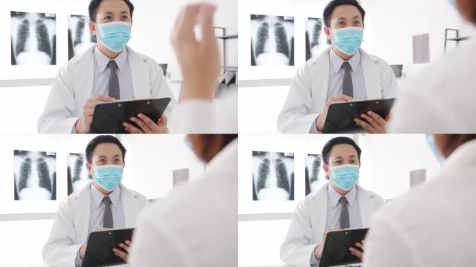 严重的亚洲男性医生戴防护口罩使用剪贴板正在传递重大新闻谈话与医院办公室的女性患者讨论结果或症状。