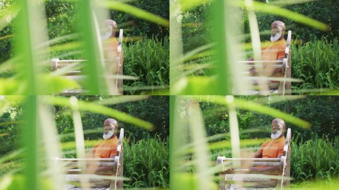 非裔美国老人坐在花园里的长椅上