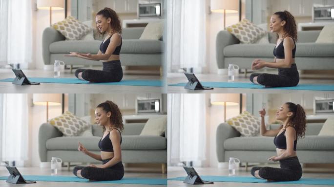 4k视频片段，一名年轻女子在家里进行瑜伽锻炼时使用数字平板电脑