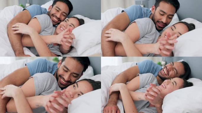 放松，爱和幸福的夫妻在家里的卧室里牵着手躺在床上休息。男人和女人拥抱，交谈和大笑，同时在他们的房子里