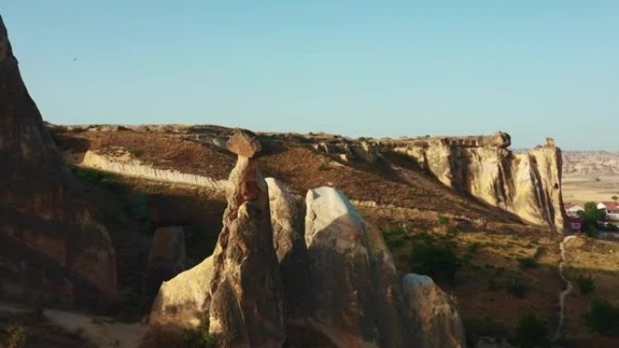 无人驾驶飞机在美丽的大石头上平移，日出天空下阳光明媚的沙漠全景揭示了土耳其的小镇。
