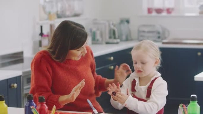 女儿在厨房里画画时向母亲展示凌乱的手