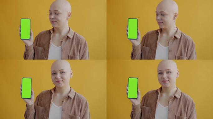迷人的年轻女子拿着智能手机的慢动作肖像，色键绿色屏幕和微笑