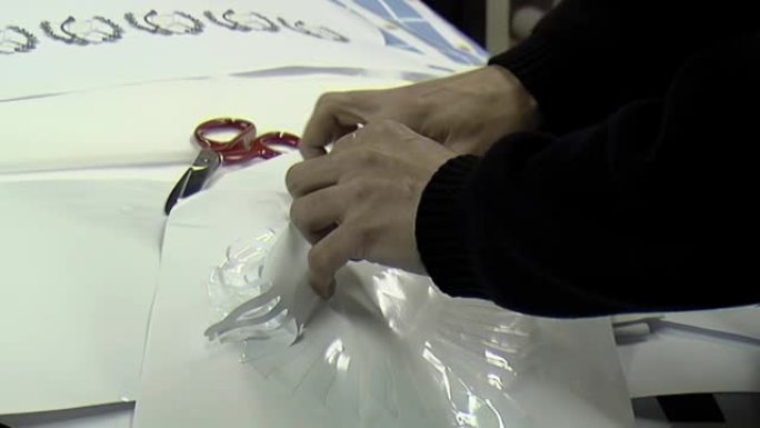 工人的手从旗厂印刷工艺部的胶膜上拉出来。特写。