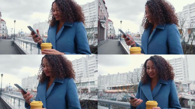 电子商务概念。美丽的年轻快乐成功的混血商业女人在城市街道上使用智能手机微笑。