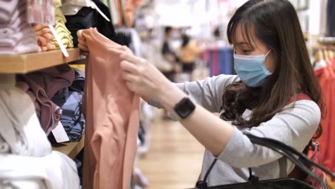 亚洲女子戴口罩在商场购物服装