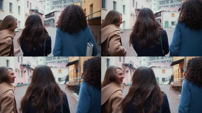 镜头跟随三个快乐的年轻女性朋友穿着外套沿着老城的街道行走，友谊的概念。