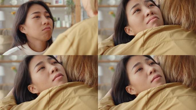 悲伤的年轻亚洲女人拥抱拥抱在家里的客厅和最好的朋友在艰难的时候互相支持，感到恶心和难过。