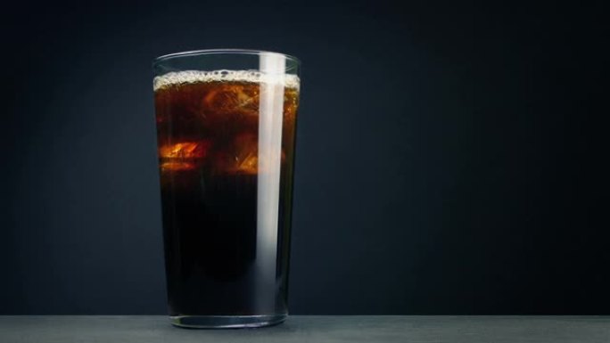 可乐饮料倒入带有冰块的玻璃杯中