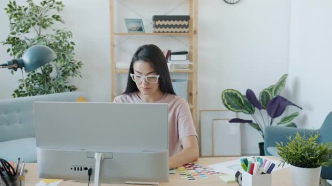 迷人的年轻亚洲女性设计师在家室内使用电脑