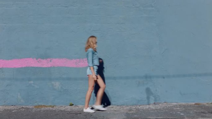 美丽的艺术家女人用粉色油漆画墙走在城市街道上自信叛逆的女性享受城市涂鸦艺术表达