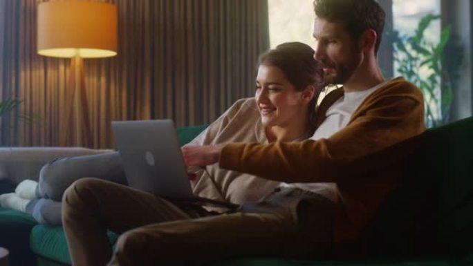 年轻夫妇坐在舒适时尚公寓的沙发上，使用笔记本电脑。男女朋友在互联网上购物，使用社交媒体，观看有趣的视