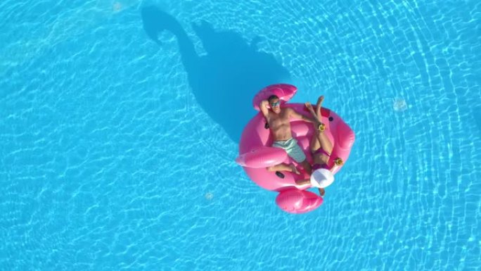 自上而下: 暑假的男人和女友在粉红色的火烈鸟漂浮物上放松