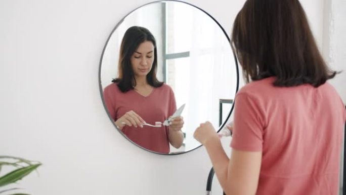 迷人的年轻女子在浴室里对着镜子刷牙的慢动作