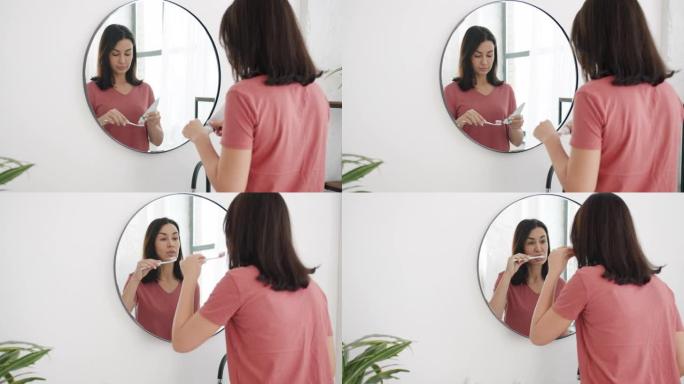 迷人的年轻女子在浴室里对着镜子刷牙的慢动作