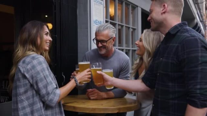 一群快乐的朋友在酒吧喝啤酒烘烤和在户外聊天