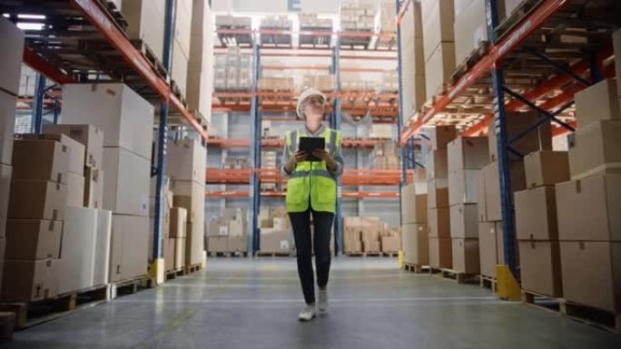 戴着安全帽的专业女工使用数字平板电脑检查库存在装满货架的零售仓库中行走。在物流、配送中心工作。后续镜