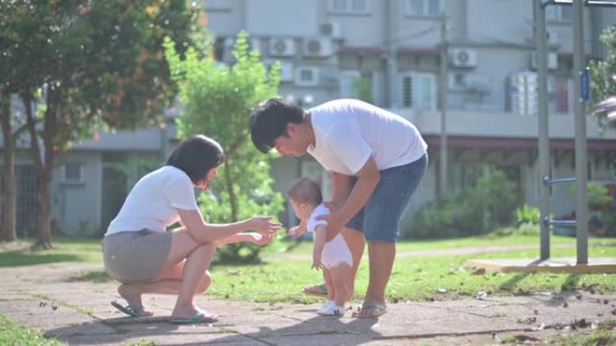 亚洲华裔家长教男婴学第一步清晨在公园散步