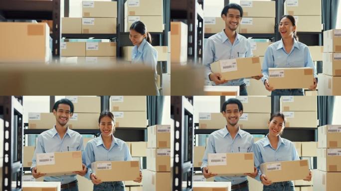 两个快乐的亚洲商业成功伙伴关系男女穿着制服衬衫背着纸板箱微笑着看着仓库里的相机。良好的合作效果，创业
