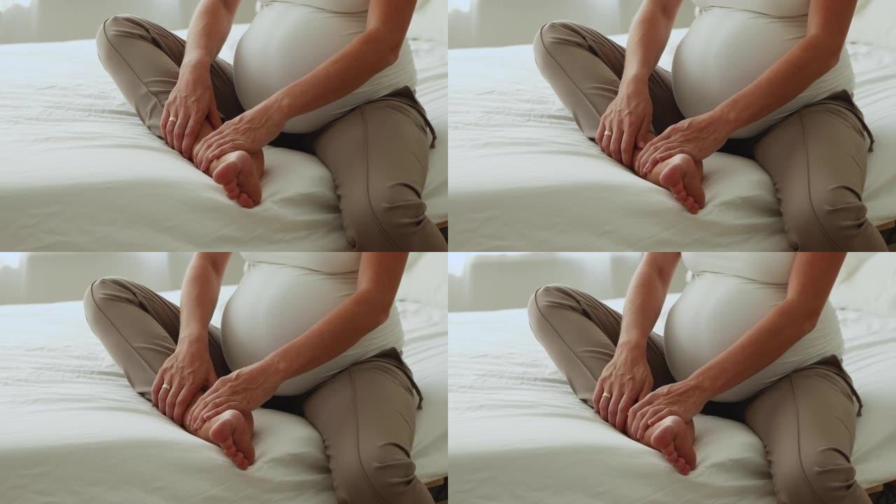 无法识别的孕妇坐在床上按摩她肿胀的脚踝