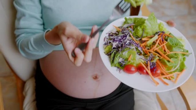 迷人的孕妇在家吃沙拉的特写