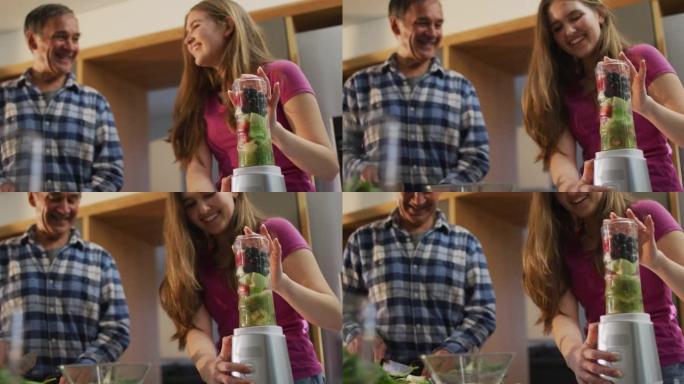 微笑的白人高级父亲和十几岁的女儿在厨房里准备健康饮料