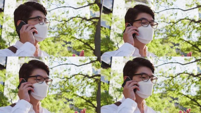 戴着口罩的亚洲男子在街上用智能手机聊天