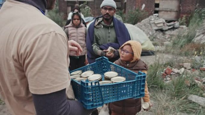 难民从志愿者那里取食罐头食品