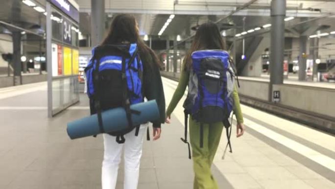 两名女性旅客在火车站平台上行走的后视图