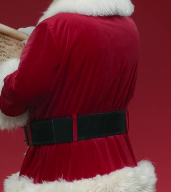 一个在红色背景上转身的圣诞老人，打开纸卷，微笑着阅读