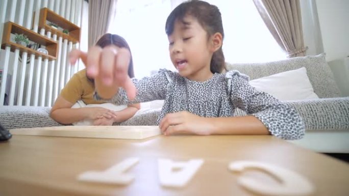 小女孩在家里的客厅玩耍和学习字母