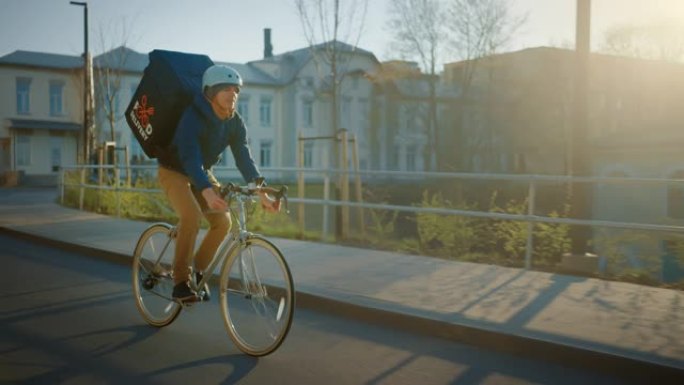 快乐的食品配送快递员穿着保暖背包骑着自行车在路上为客户交付订单和包裹。现代城市中阳光明媚的日子，拥有