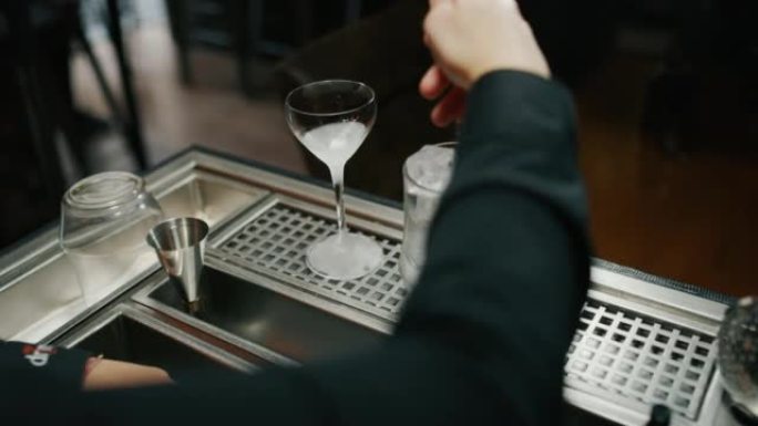 专业调酒师的特写镜头正在为酒吧或迪斯科俱乐部的顾客准备带有专业水晶持久冰块的酒精鸡尾酒。