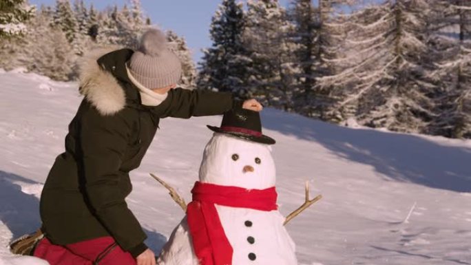 肖像: 快乐的女人在一个有趣的雪人上戴上黑帽子后微笑。