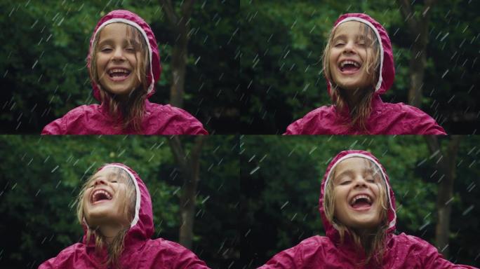 一个穿着粉红色雨衣的快乐小女孩在雨中快乐地站着，被大自然和树木包围着。女孩微笑着，在雨天独自在外面玩