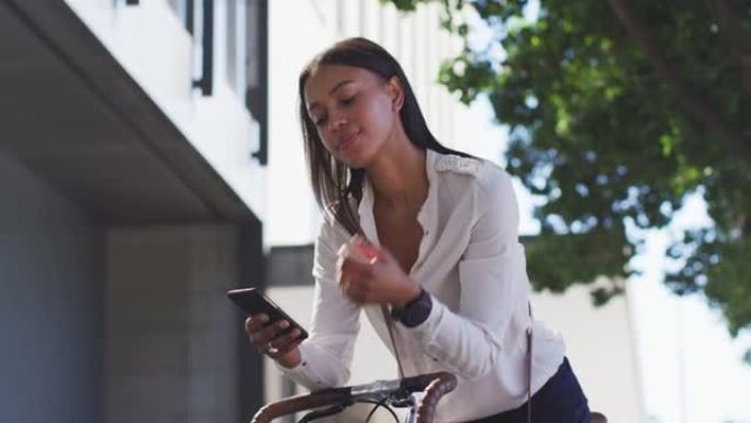 非裔美国妇女在街上使用智能手机倚靠自行车