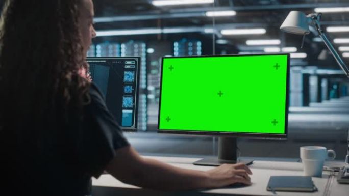 高科技数据中心服务器: 黑色女性IT专家在绿屏色度关键计算机上工作。监控网络服务、云计算、分析设施、