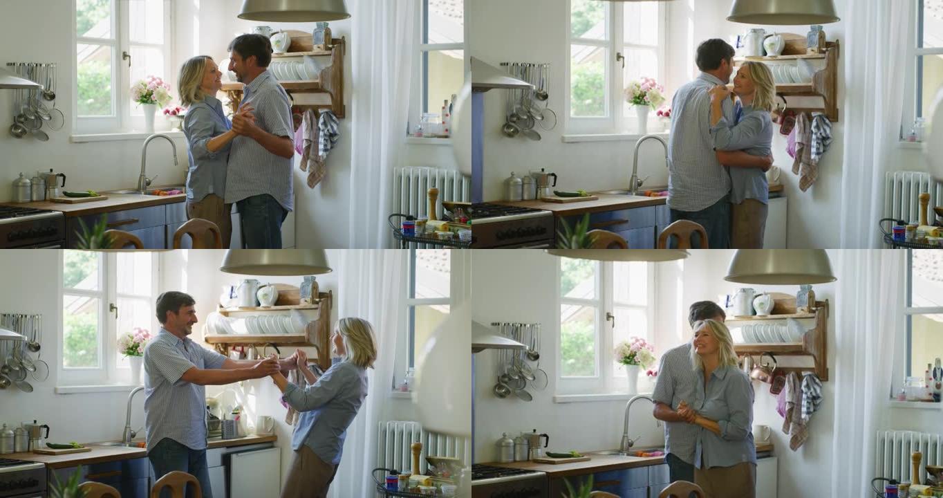 可爱的快乐成熟夫妇的真实照片是享受在一起的时光，并在家里的厨房里跳舞庆祝他们永恒的爱。