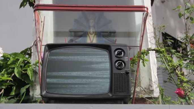 圣母玛利亚雕塑和复古电视打开绿色屏幕。4K。