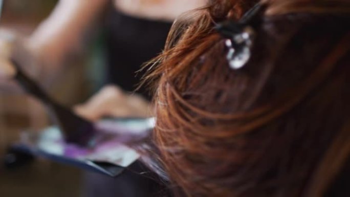 女美发师在发廊戴口罩的女性顾客的头发垂死