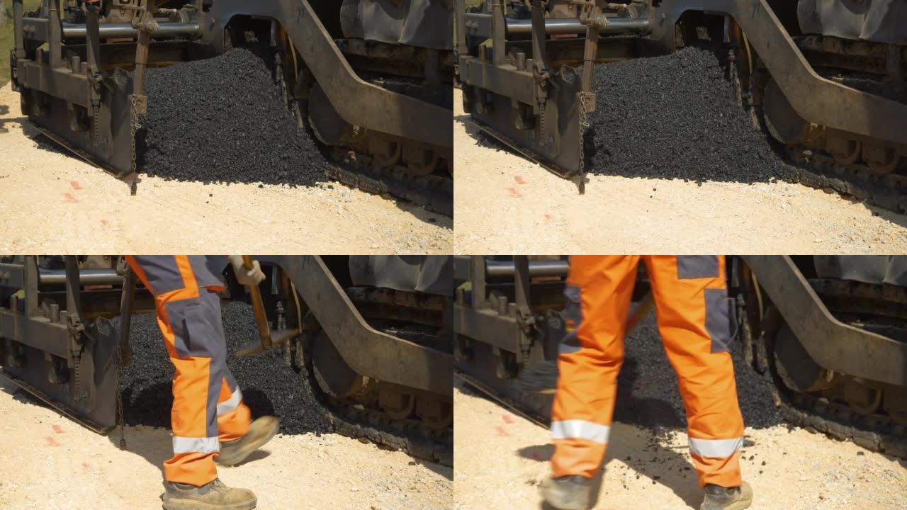 特写: 工人拿起一铲沥青摊铺机倾倒的新鲜沥青