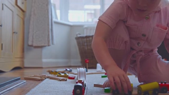 家里女孩在地毯上玩木制火车玩具的特写