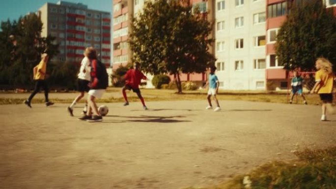 在东欧后院踢足球的邻居孩子。年轻的足球运动员运球，传球，进球。男孩和女孩拥抱，庆祝胜利。宽手持跟踪镜