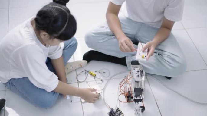 一组男孩和女孩的构建和研究机器人STEM编程软件和修复