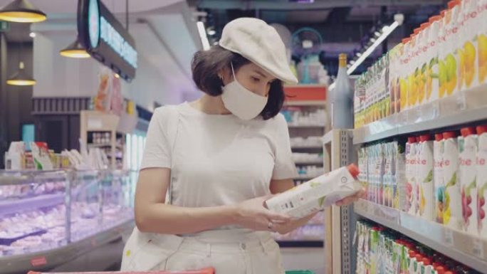 视频年轻女子戴着医用口罩的女孩在超市购买罐头食品