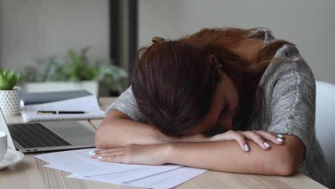 过度劳累的学生女孩睡在办公桌上感到太累了