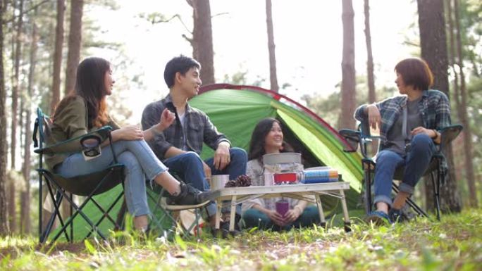 一群朋友在松树露营地的户外露营中，在帐篷前享受