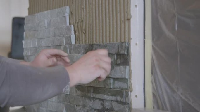 特写: 建筑商将瓷砖牢固地压在被砂浆覆盖的墙上。