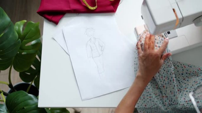用缝纫机工作的女性手的特写镜头创造了新的设计师服装